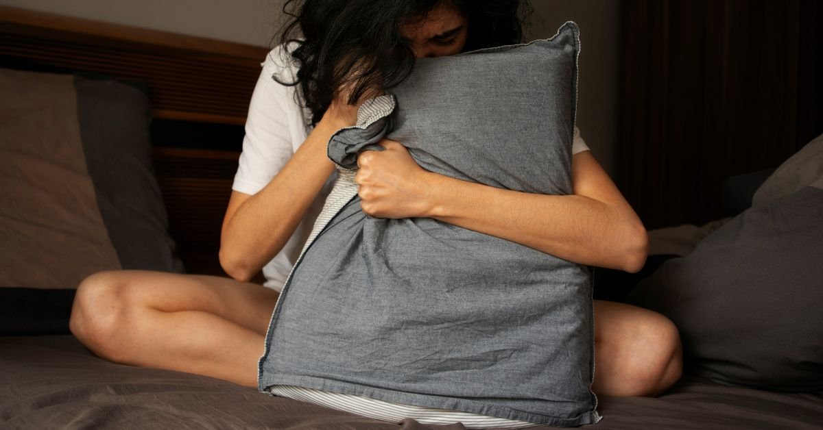 A woman holding a grey pillow not able to sleep